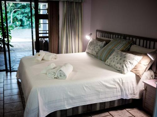 a bedroom with a large white bed with towels on it at Africa's Eden Guesthouse in Pietermaritzburg