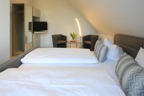 a large white bed in a room with chairs at Weinstube Schwalbennest in Karlstadt