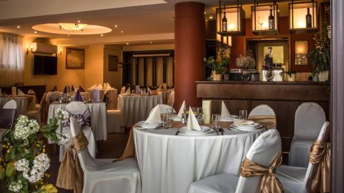 a restaurant with white tables and chairs and flowers at Hotel Bobbio in Budapest