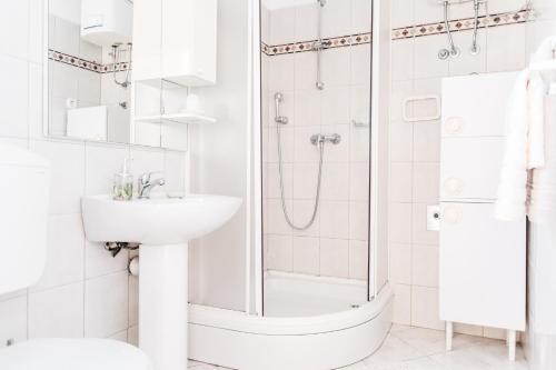 a white bathroom with a shower and a sink at Apartments Tudić in Brodarica