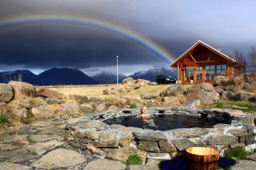 a rainbow over a pool of water with a cabin at Hestasport Cottages in Varmahlid