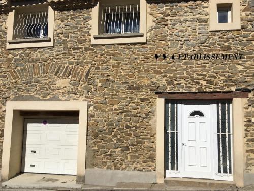 duas portas brancas do lado de um edifício de pedra em VVA em Conques-sur-Orbiel