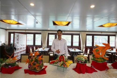 a man standing in front of a table in a restaurant at Halong Sapphire Cruises in Ha Long