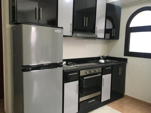 d'une cuisine équipée d'un réfrigérateur en acier inoxydable et de placards noirs. dans l'établissement Sea View One Bedroom in Hurghada - H105, à Hurghada