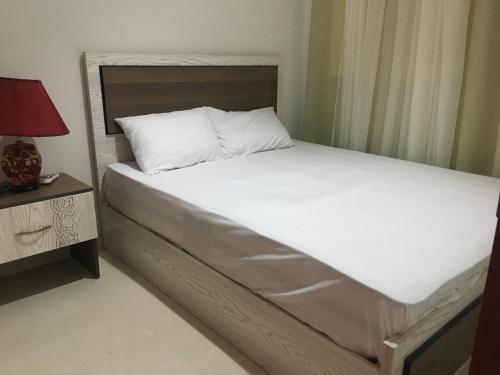 un lit avec des draps blancs et une lampe rouge sur une table dans l'établissement Sea View One Bedroom in Hurghada - H105, à Hurghada
