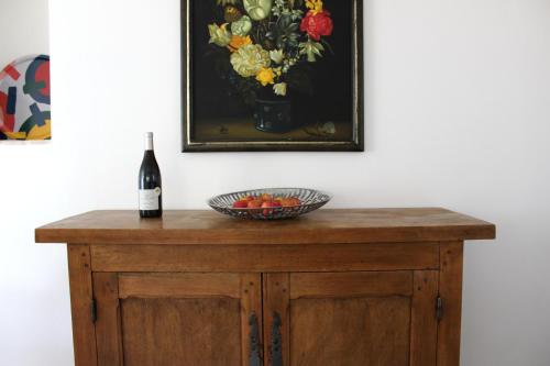 a bottle of wine and a bowl of fruit on a table at Les Airis in Avignon