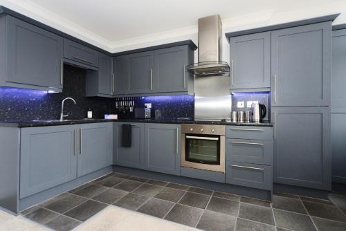 a kitchen with blue cabinets and a sink at Beautiful Apartment near Bournemouth, Poole & Sandbanks in Poole