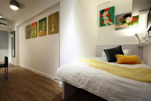 a bedroom with a bed and some paintings on the wall at Apple lnn Causeway Bay in Hong Kong