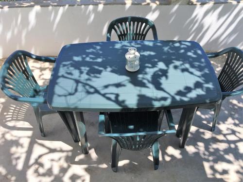 een blauwe tafel met twee stoelen en een fles erop bij Family house Bacalja in Preko
