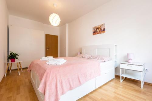 a white bedroom with a bed and a table at Spacious Apartment in the Old Town of Bratislava in Bratislava