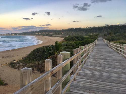 a wooden boardwalk to the beach at sunset at Walk to the Beach 2Min, Cozy, Boutique, Pool, Palmeras Del Mar Isabela in Isabela