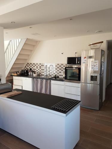 une grande cuisine avec des armoires et des appareils blancs dans l'établissement DOMAINE DE MALGARNI, à Clémont