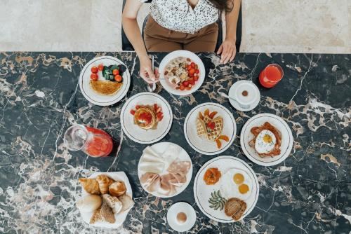 Una mujer parada en una mesa con platos de comida. en Grand Hotel Croce Di Malta, en Montecatini Terme
