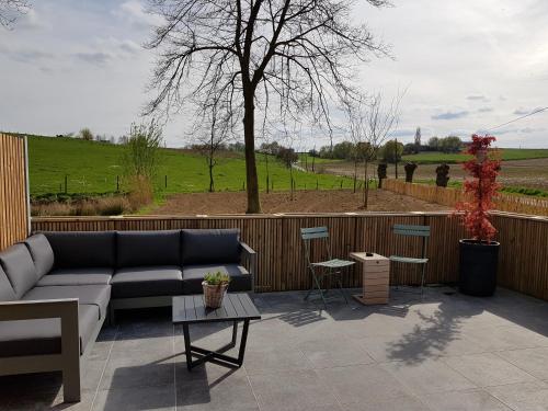 a patio with a couch and tables and a tree at Sparhof in Dranouter