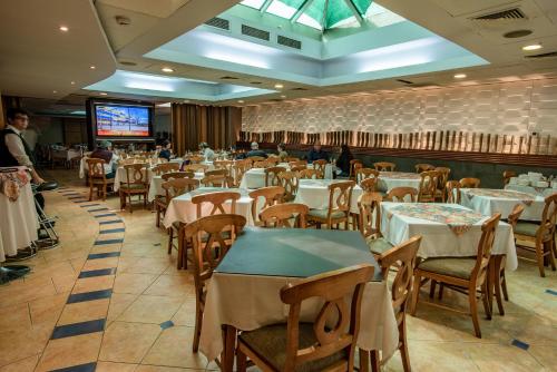 a dining room with tables and chairs and a tv at Hotel Libertador in Santiago