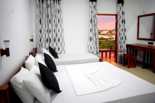 a bedroom with two beds and a desk and a window at Blue Sky Hotel Yala in Yala