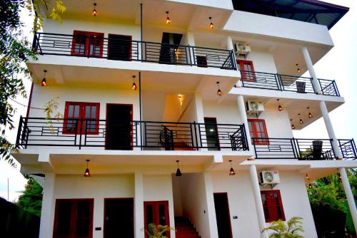 a white building with red doors and balconies at Blue Sky Hotel Yala in Yala