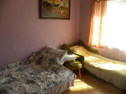 a bedroom with two beds and a window and a chair at Stajnia Grazyny Mikorowo 46 in Czarna Dąbrówka
