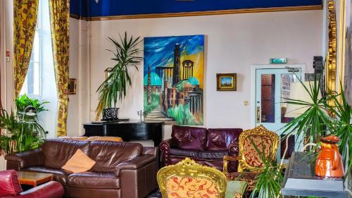 a living room with leather furniture and a painting on the wall at Castle Rock Hostel - Adults Only in Edinburgh