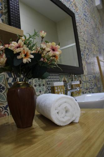 ein Badezimmer mit einer Vase aus Blumen und einem Handtuch in der Unterkunft FeelCoimbra Apartamento Santa Cruz in Coimbra