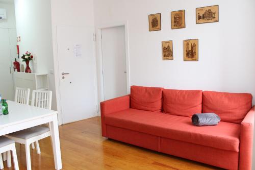 a red couch in a living room with a table at FeelCoimbra Apartamento Santa Cruz in Coimbra