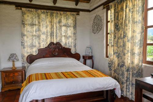 a bedroom with a bed and curtains and a window at Hostería Colibri Aeropuerto in Tababela