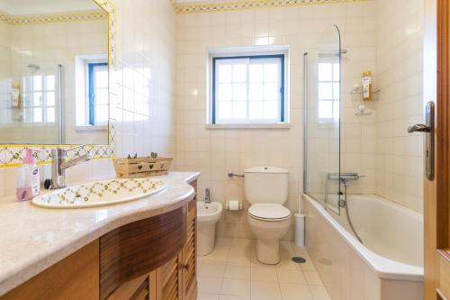 Liv In Ericeira Guest House في إيريسييرا: حمام مع مرحاض وحوض استحمام ومغسلة