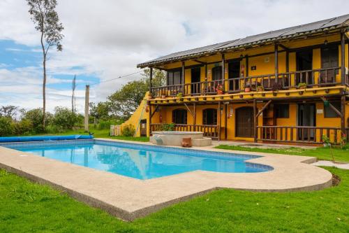 a house with a swimming pool in front of a building at Hostería Colibri Aeropuerto in Tababela