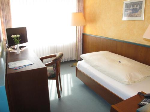 a bedroom with a bed and a desk with a computer at Hotel Reifenstein in Kleinbartloff