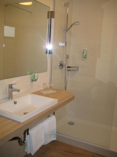 a bathroom with a sink and a shower with a mirror at Hotel Zur Linde in Lauf