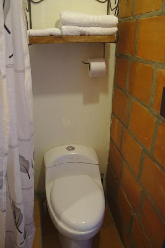 a bathroom with a white toilet and towels on a shelf at Soñarte Reserva Natural in Córdoba