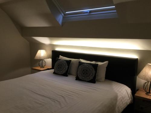 a bedroom with a white bed with two lamps at Hotel Côté Cour in Durbuy