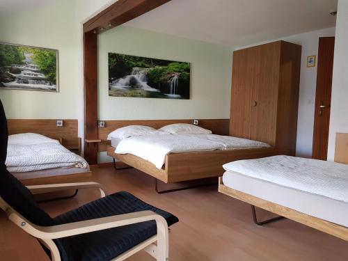 una habitación con 3 camas y una silla. en Garni-Hotel Mühletal en Stein am Rhein