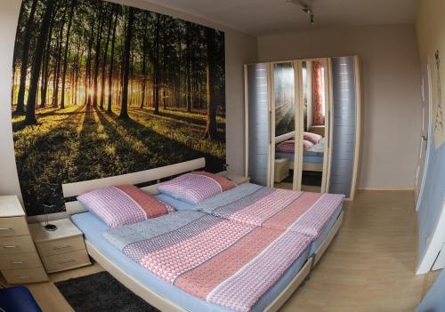 a bedroom with a bed with a forest mural on the wall at Ferienwohnung Wanderurlaub Thüringen in Schmalkalden