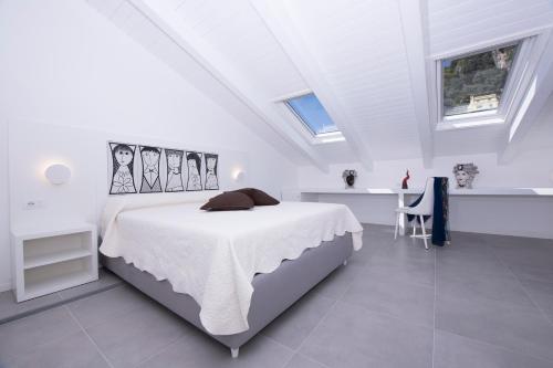 a white bedroom with a bed in a room with windows at Zia Pupetta Suites in Amalfi