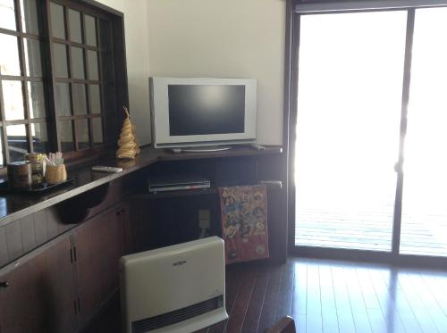 a living room with a television on a counter at Minshuku Ippu in Yamanouchi