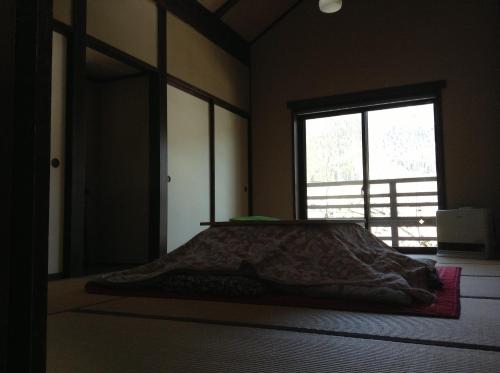 a bed in a room with a window at Minshuku Ippu in Yamanouchi