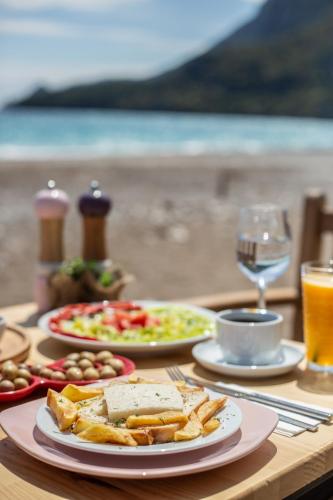 a table with plates of food and a glass of wine at Kara Kedi Beach Bungalow in Cıralı