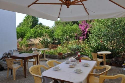 a patio with tables and chairs and an umbrella at Masseria San Nicola in Patù