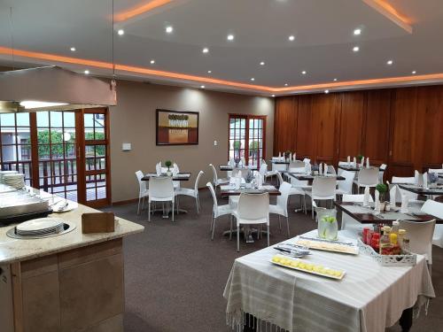 um restaurante com mesas brancas e cadeiras brancas em Shonalanga Lodge em Vryheid