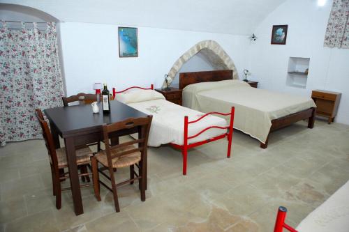 a bedroom with two beds and a table and chairs at Masseria San Nicola in Patù
