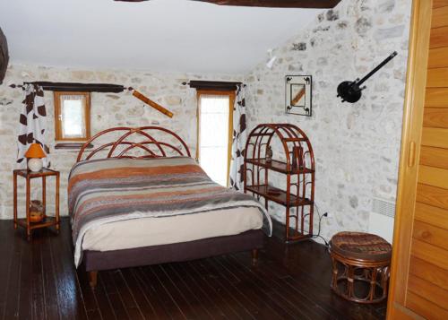 une chambre avec un lit et un mur en pierre dans l'établissement Gîtes Chez Belliveau, à Meursac