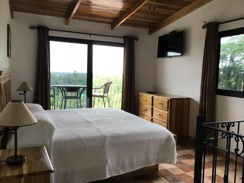 a bedroom with a bed and a balcony with a table at Hotel Los Cielos Del Caribe in Cahuita