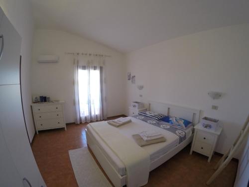 een witte slaapkamer met een bed en een raam bij Appartamento a Vignola Mare in Aglientu