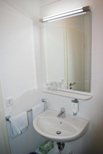 a white bathroom with a sink and a mirror at Hotel Garni am Hechenberg in Mainz