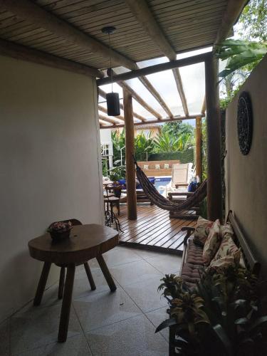 a living room with a patio with a hammock and a table at Mares de Camburizinho in Camburi