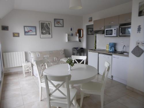 a kitchen and dining room with a white table and chairs at Appartement Kervoyal in Kervoyal