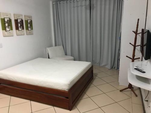 um quarto com uma cama, uma cadeira e uma secretária em Loft da prainha 117 em Arraial do Cabo