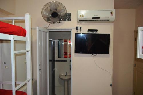 a room with a tv on the wall and a bathroom at Solar Hostel Beach Copacabana in Rio de Janeiro