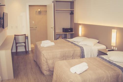 una habitación de hotel con 3 camas y una silla en HOTEL LUAR ATLANTICO, en Balneário Camboriú